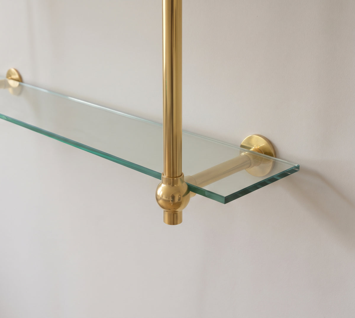 Close-up of a solid brass ball joint and wall flange supporting a 10 mm glass shelf