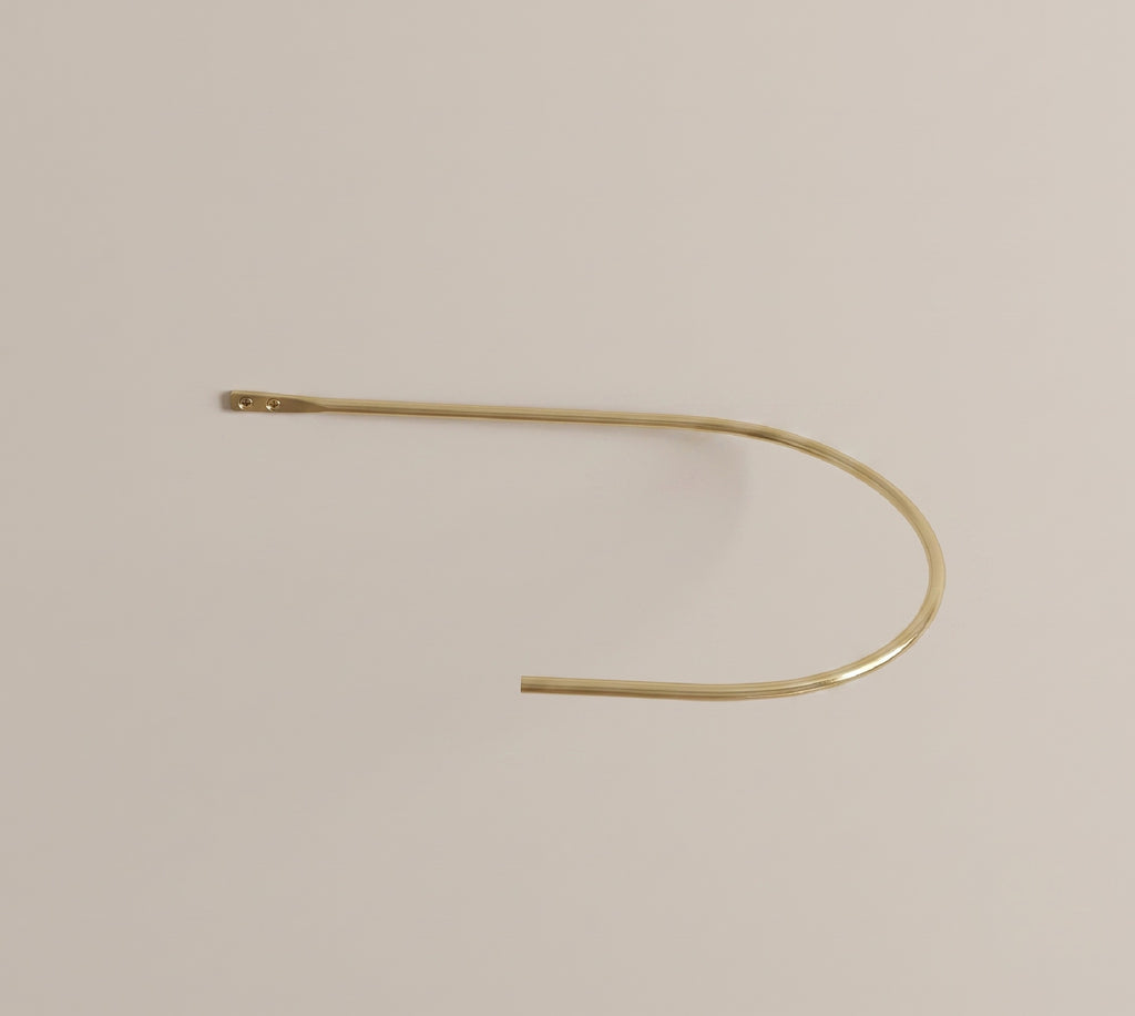 Curved brass curtain holdback holding a drape to the side of a window