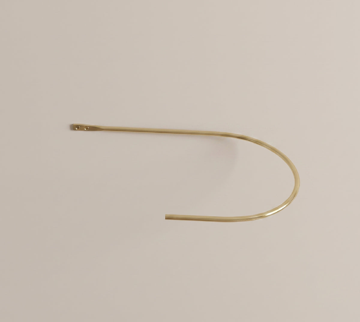 Curved brass curtain holdback holding a drape to the side of a window