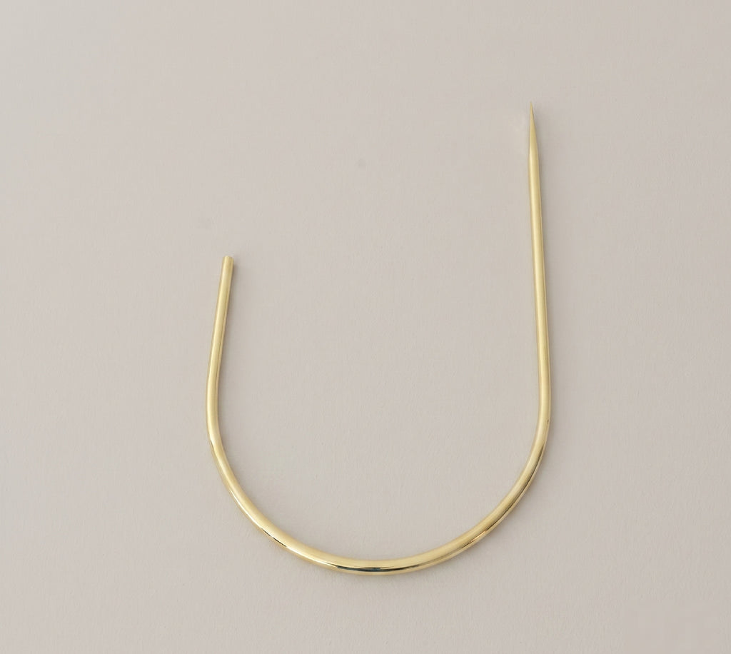 Detail of the curved arm on a solid brass curtain holdback