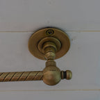 Curved open brass toilet tissue holder with decorative engraving